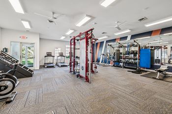 A gym with a variety of equipment including a weight rack, treadmill, and exercise bench.